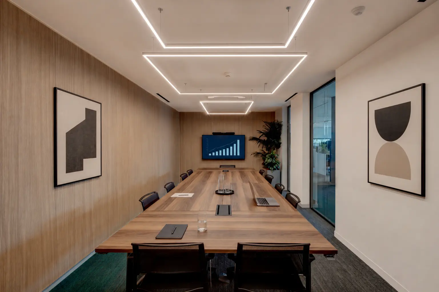 Enclosed meeting room with a long table, integrated screen and acoustic wall panels